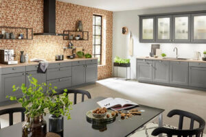Gemütliche Landhausküche mit grauen Holzfronten, rustikaler Holzarbeitsplatte und nostalgischen Accessoires.