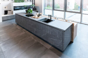 Moderne grifflose Einbauküche mit dunklen Lava-Fronten und weißen Schränken.