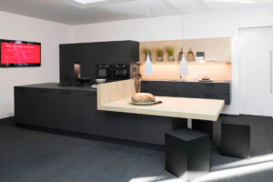Moderne schwarze Küche mit hellen Holzelementen, integrierten Elektrogeräten in den Hochschränken und sichtbaren Griffen für eine elegante und funktionale Optik.