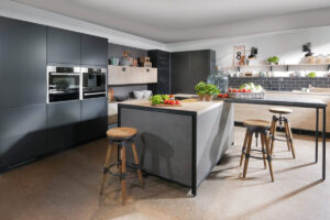 Moderne Küche mit grauen Betonoberflächen und warmen Holzelementen. Eine großzügige Kochinsel schafft klare Zonen für Kochen und Essen, die funktional und ästhetisch den Raum strukturieren.